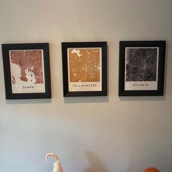 Three framed city map posters of Tampa, Tallahassee and Atlanta hung on a wall